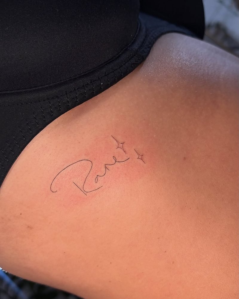 A fine line script tattoo with two small stars