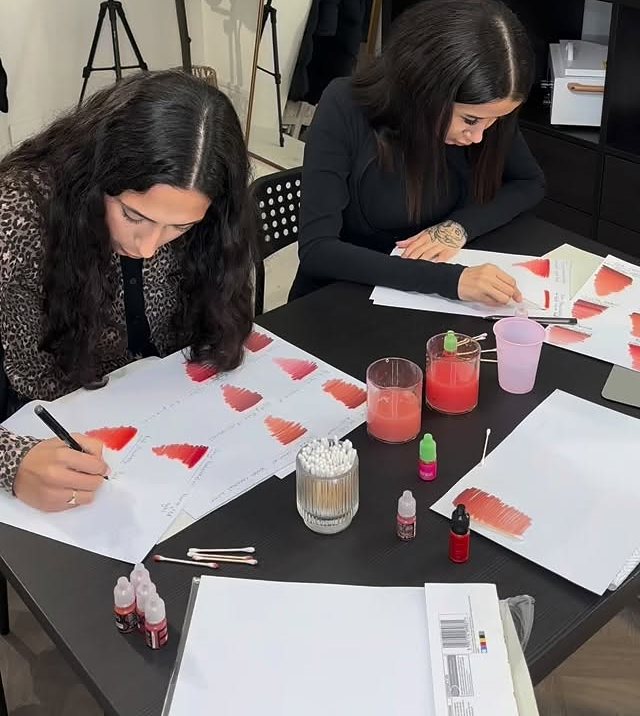 Two students practising lip blush on paper during training